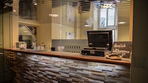 Un área de recepción con pared de piedra, mostrador de recepción, una computadora y un cartel de bienvenida.