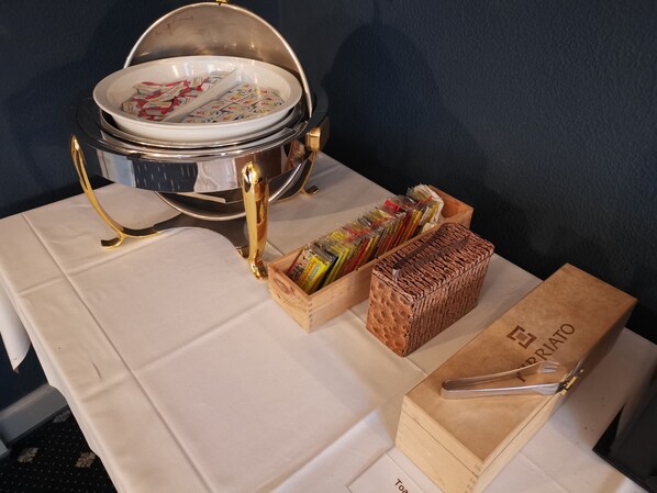 A buffet setup with a large bowl, a wooden box labeled "TOAST," and a tray of packaged food items.