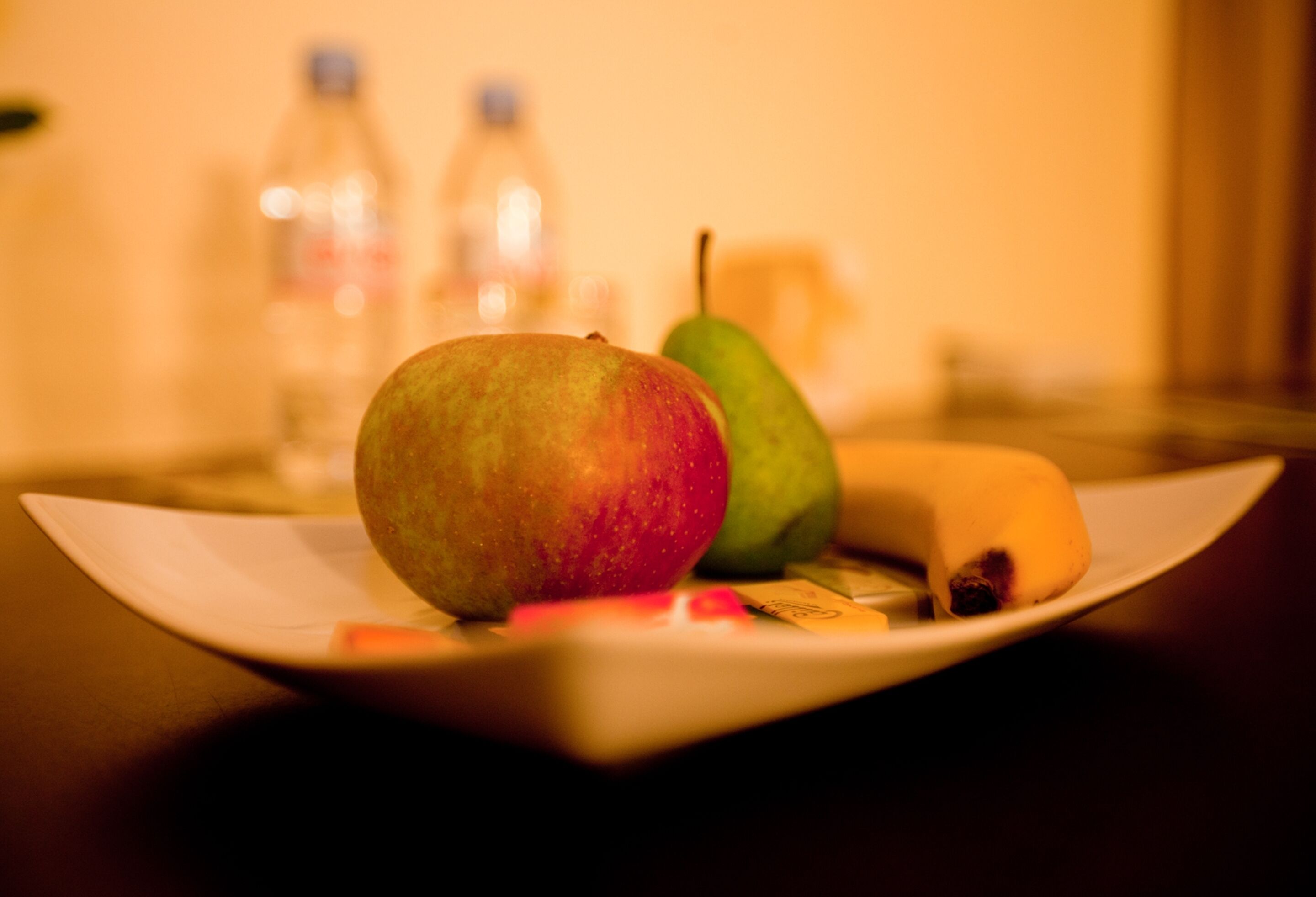 A plate with a red apple, a green pear, and a banana.