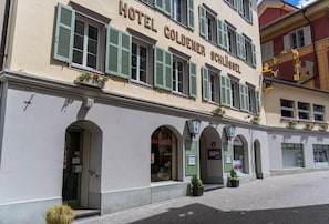 Un edificio con el letrero "HOTEL GOLDENER SCHLÜSSEL" y numerosas ventanas con contraventanas verdes.