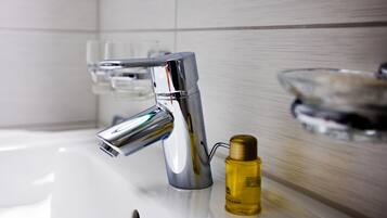 A modern bathroom with a chrome faucet, a glass soap dish, and a bottle of liquid soap.