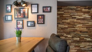 Un comedor con una mesa de madera, sillas y una pared decorada con marcos y un panel de madera.