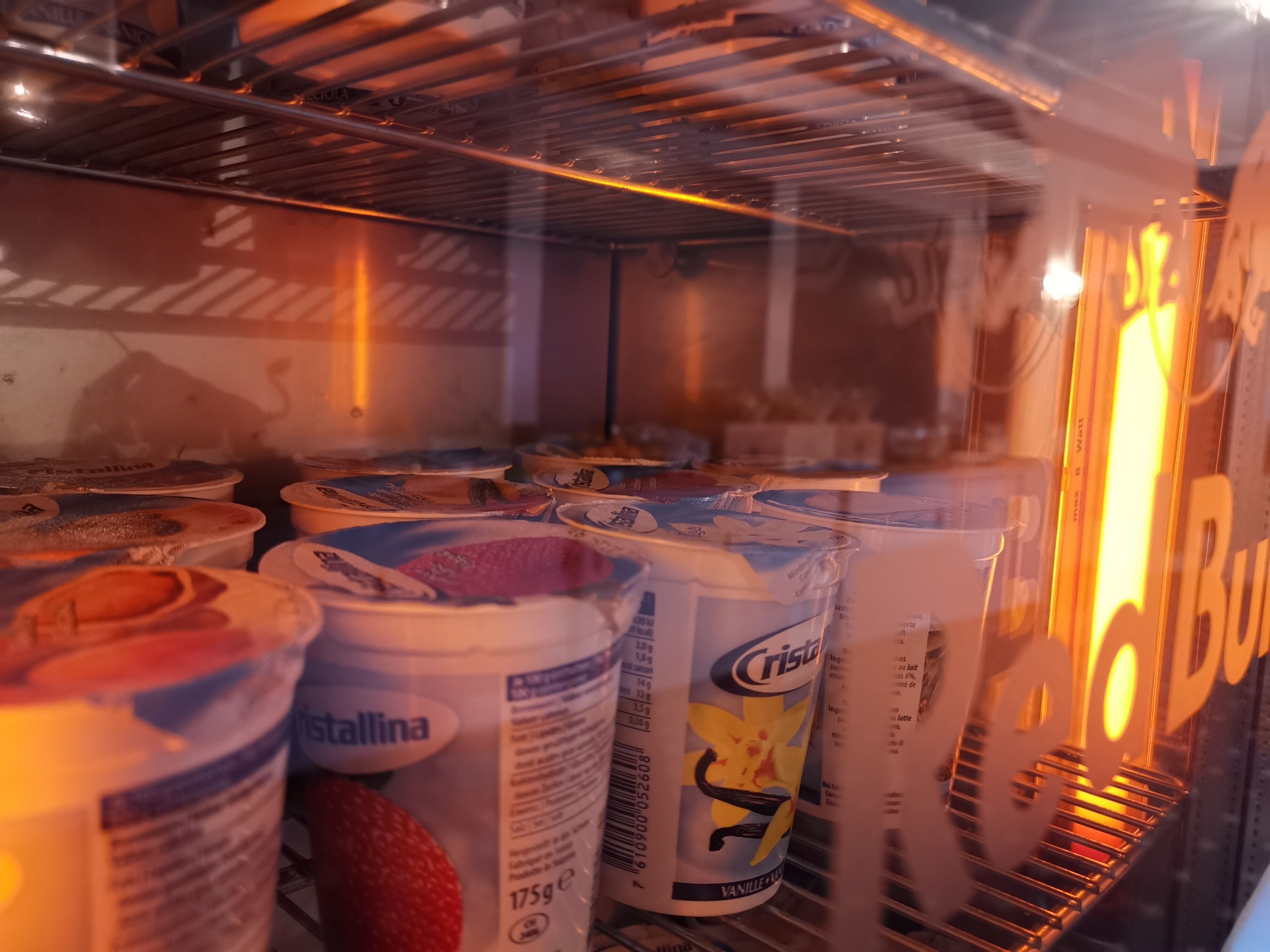 A refrigerator stocked with various food items, including cans and bottles, likely in a hotel or similar accommodation.