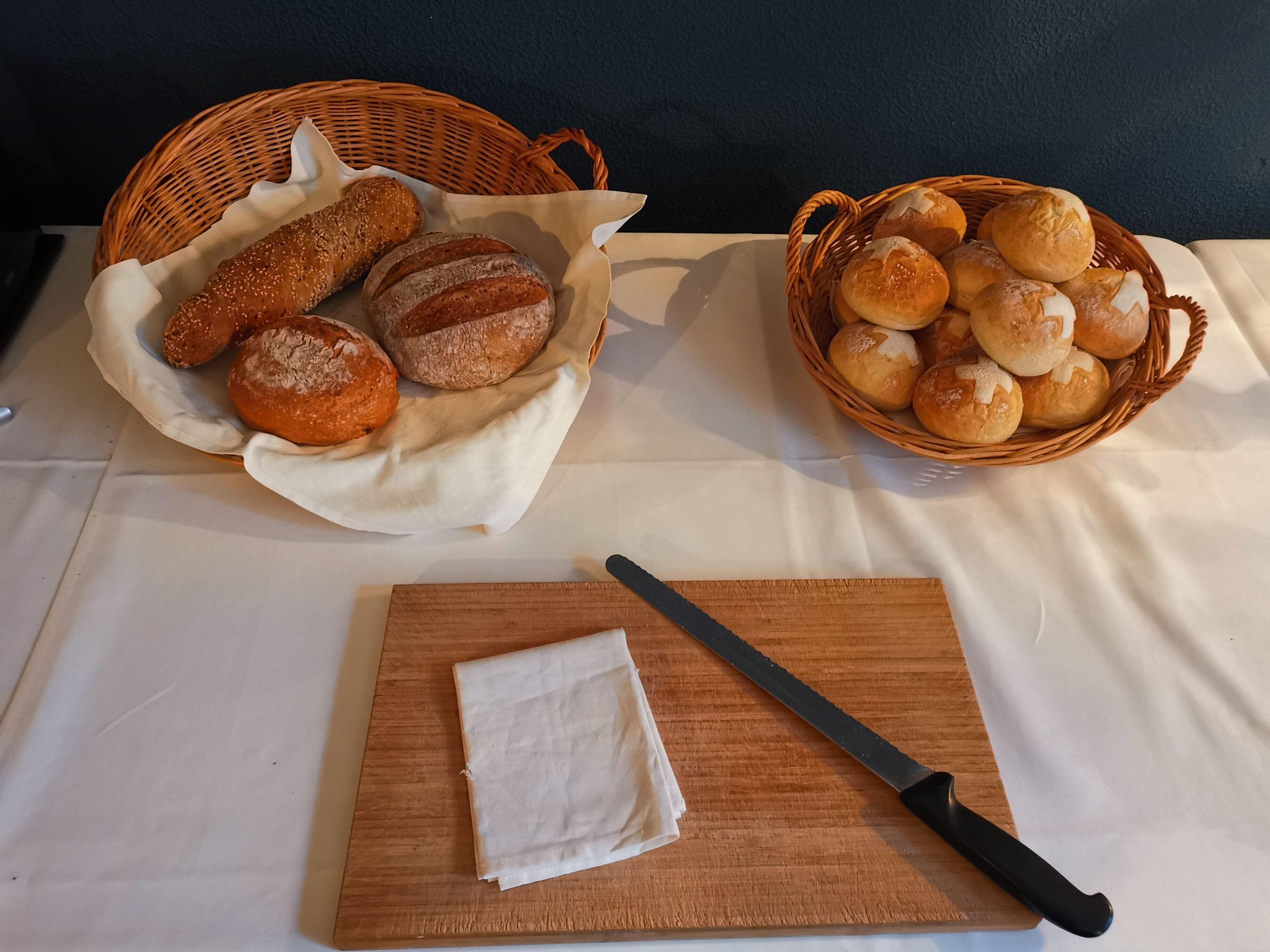 Two wicker baskets filled with various breads on a table.