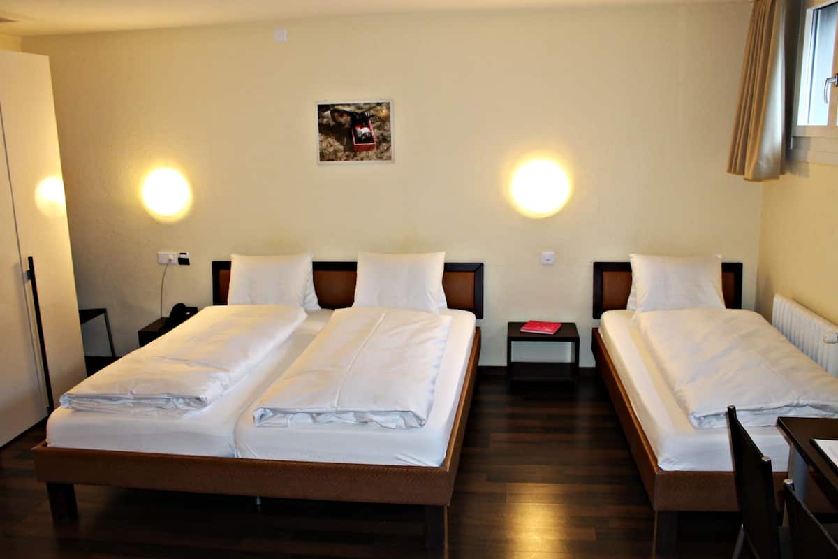 A hotel room with two single beds, a desk, and a chair.