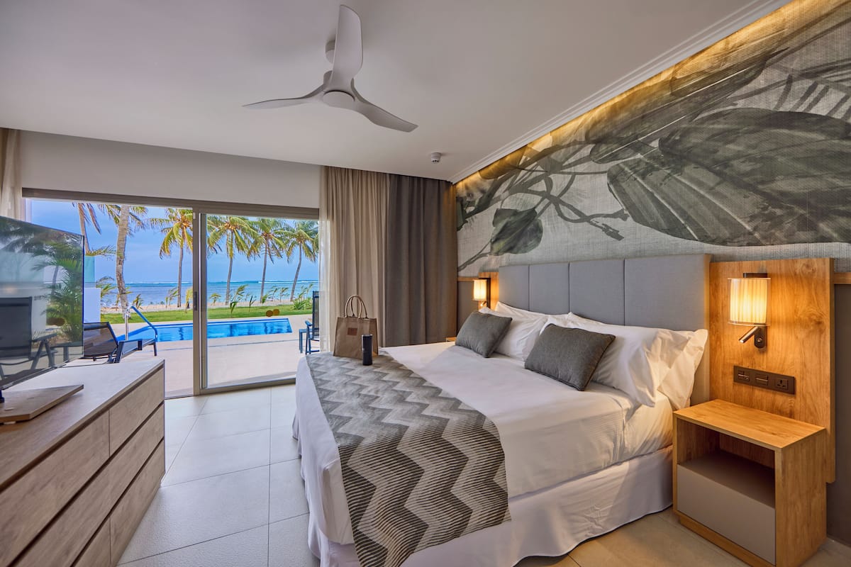 A modern hotel room with a large bed, a desk, and a view of the ocean.