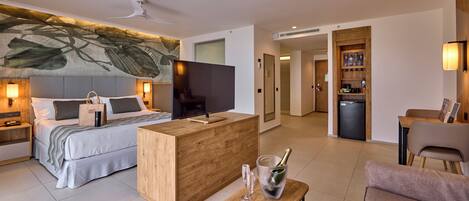 Una habitación de hotel moderna con una cama, un escritorio de madera, un televisor y un minibar.