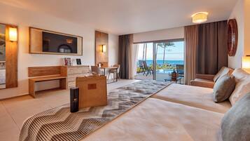 Een moderne hotelkamer met een groot bed, een bureau, een stoel, een bank en een balkon met uitzicht op zee.