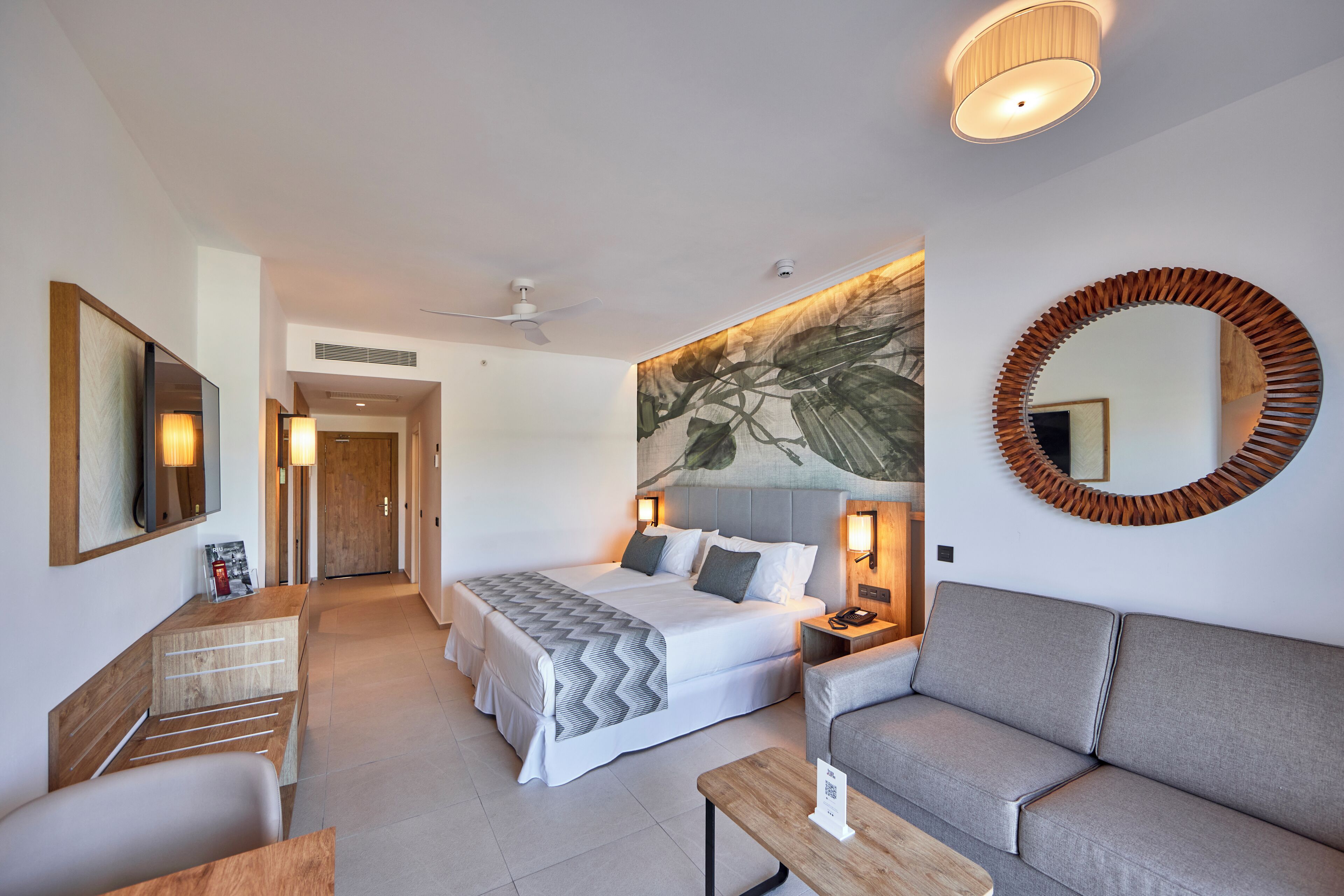 Una habitación de hotel con una cama, un sofá, un escritorio y un espejo.