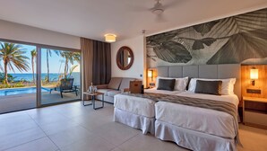 A hotel room with a large bed, a sofa, a small table, and a view of the ocean.