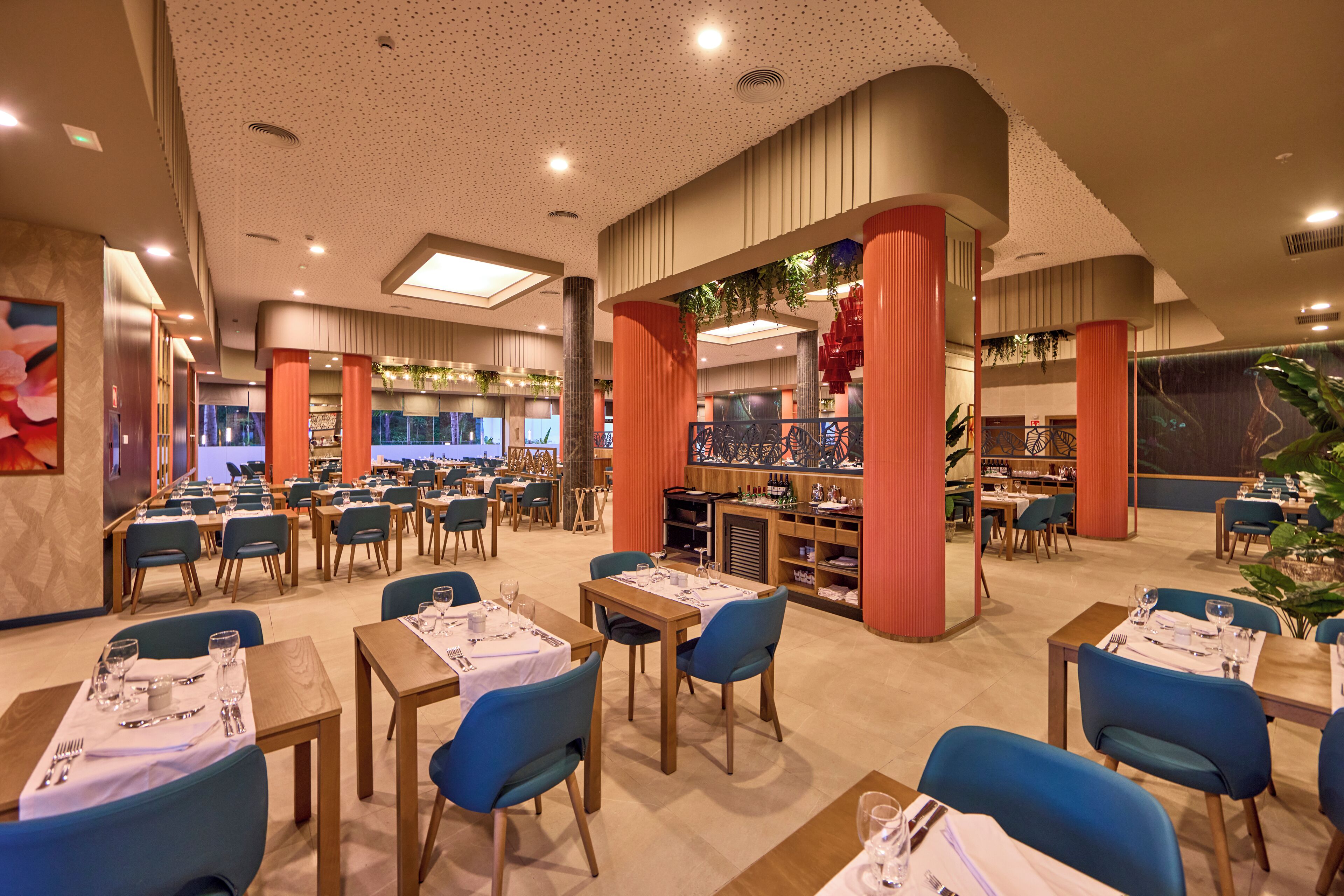 Een ruim restaurant met meerdere eetgedeeltes, hoge plafonds en modern decor.