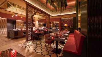 Un restaurante con piso estampado, asientos rojos y plantas colgantes.