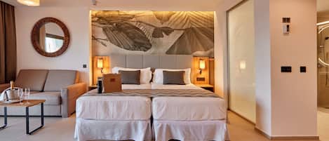 Une chambre d’hôtel moderne avec un grand lit, un canapé, une petite table avec des verres et un miroir fixé au mur.