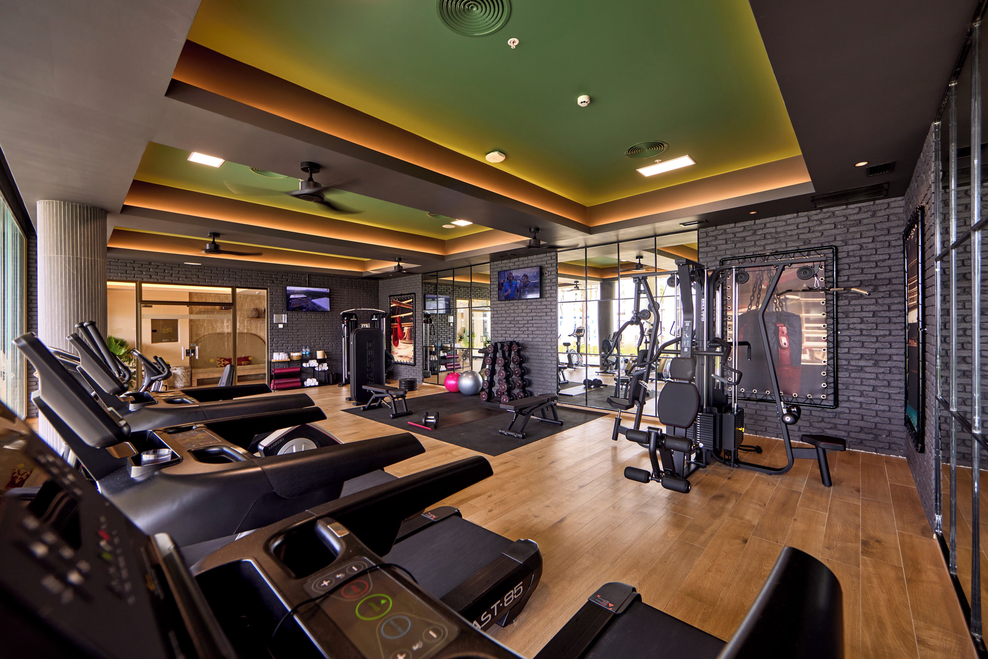 Un gimnasio moderno con equipo de cardio, máquinas de pesas y diseño de pared de ladrillo.