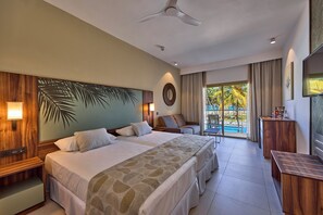 A hotel room with a large bed, a desk, a chair, a TV, and a view of the pool.