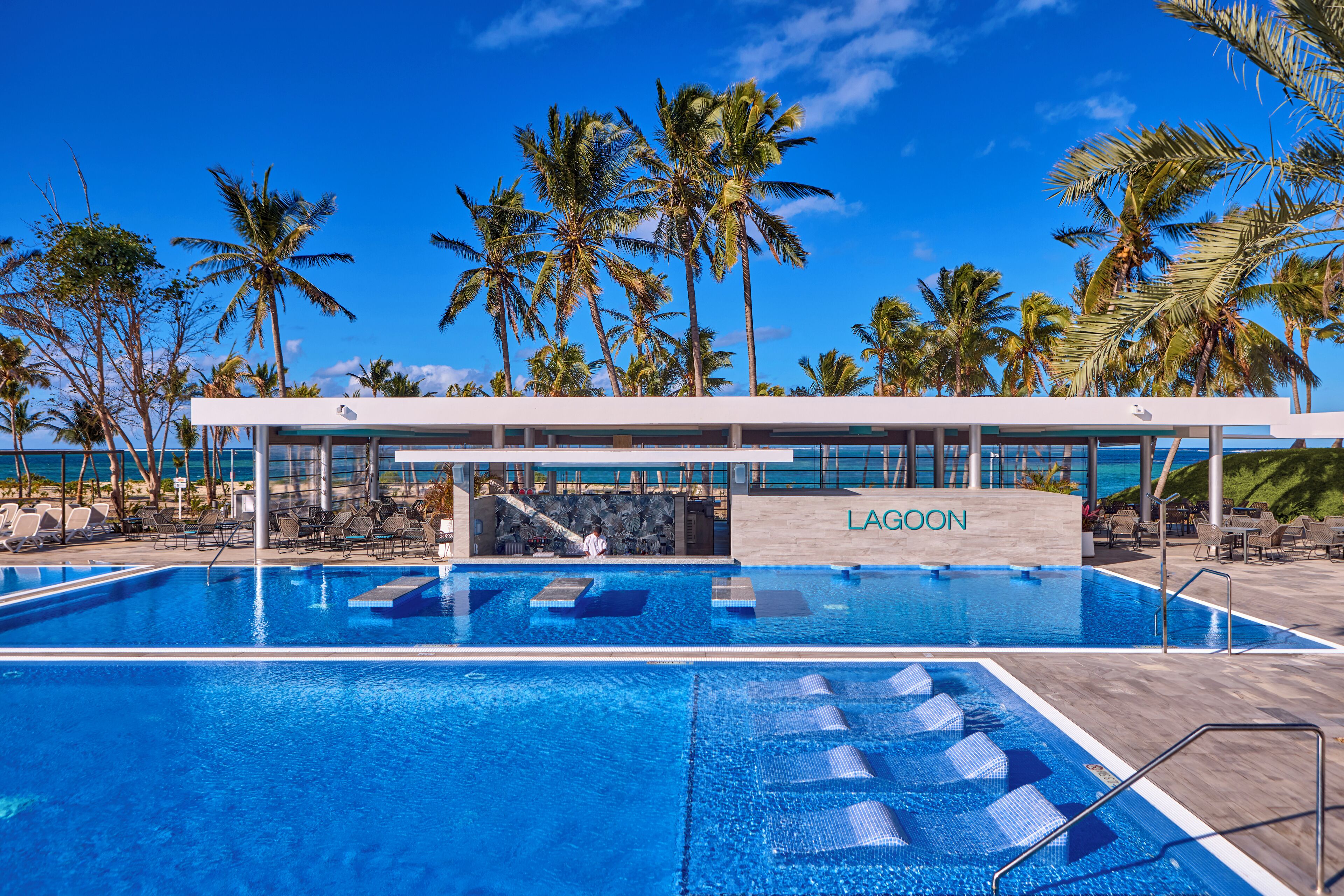 A swimming pool with lounge chairs and palm trees, surrounded by a building labeled "LAGOON".
