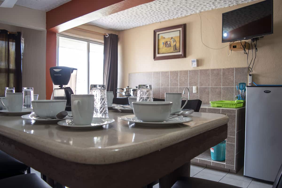 A kitchen with a dining table set for four, a coffee maker, and a refrigerator.