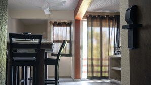 Un comedor con una mesa, sillas, ventilador de techo y una ventana con cortinas.