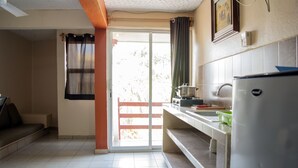 Una cocina con refrigerador, estufa y lavaplatos. Hay una puerta corrediza de vidrio que da a un balcón.
