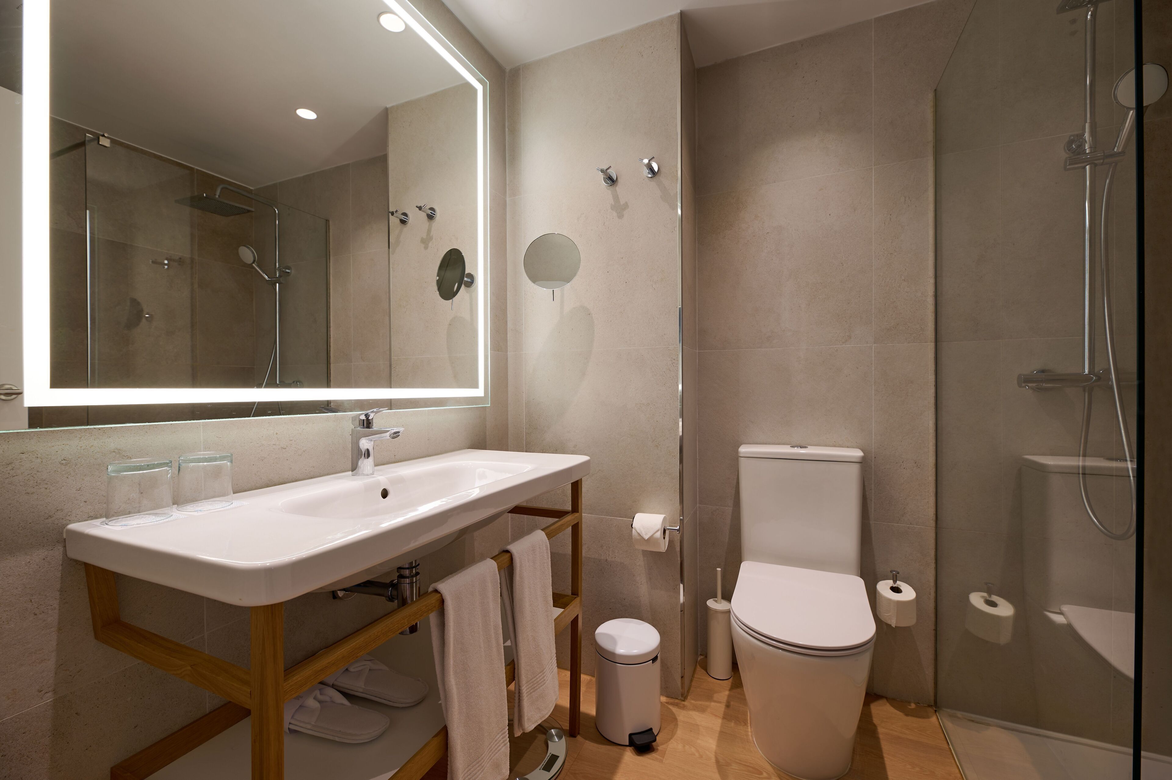 Une salle de bain moderne avec un grand miroir, un lavabo, des toilettes et un espace douche.