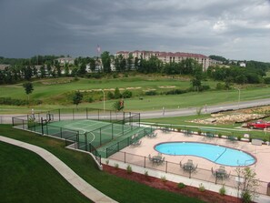 A golf course with a pool area, surrounded by a fence and a building in the background.