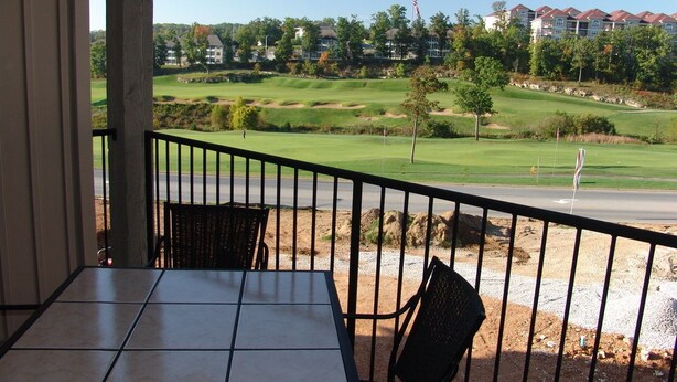 A balcony with a view of a golf course and residential buildings. - Royal Links (Branson)