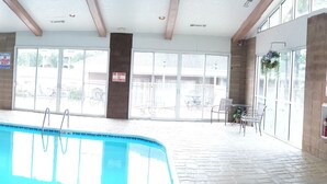 An indoor swimming pool with clear glass walls, a tiled floor, and a wooden ceiling. - Royal Links (Branson)