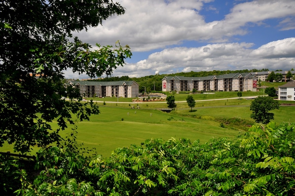 A hotel with multiple buildings, a well-maintained lawn, and a bridge.
