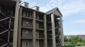 A multi-story apartment building with a central courtyard, balconies, and a stairwell. - Royal Links (Branson)