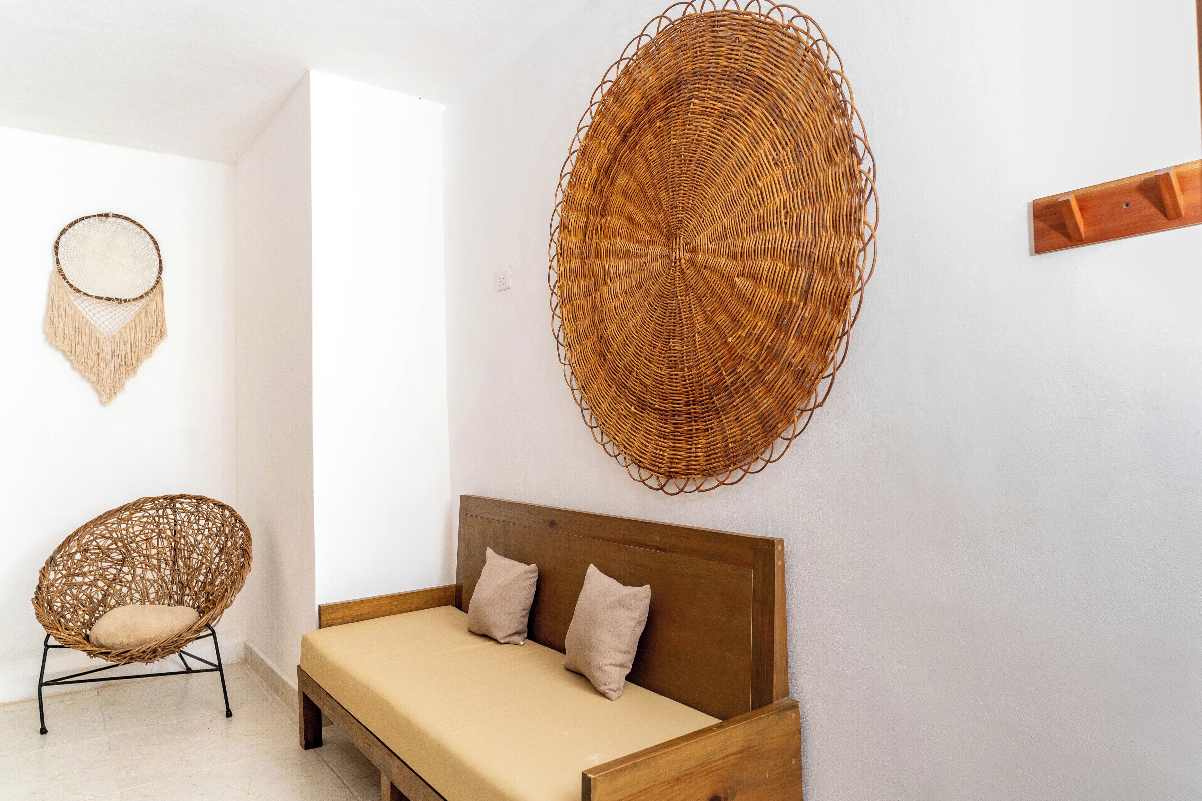 A room with a wooden bed, a woven wall hanging, and a woven chair.