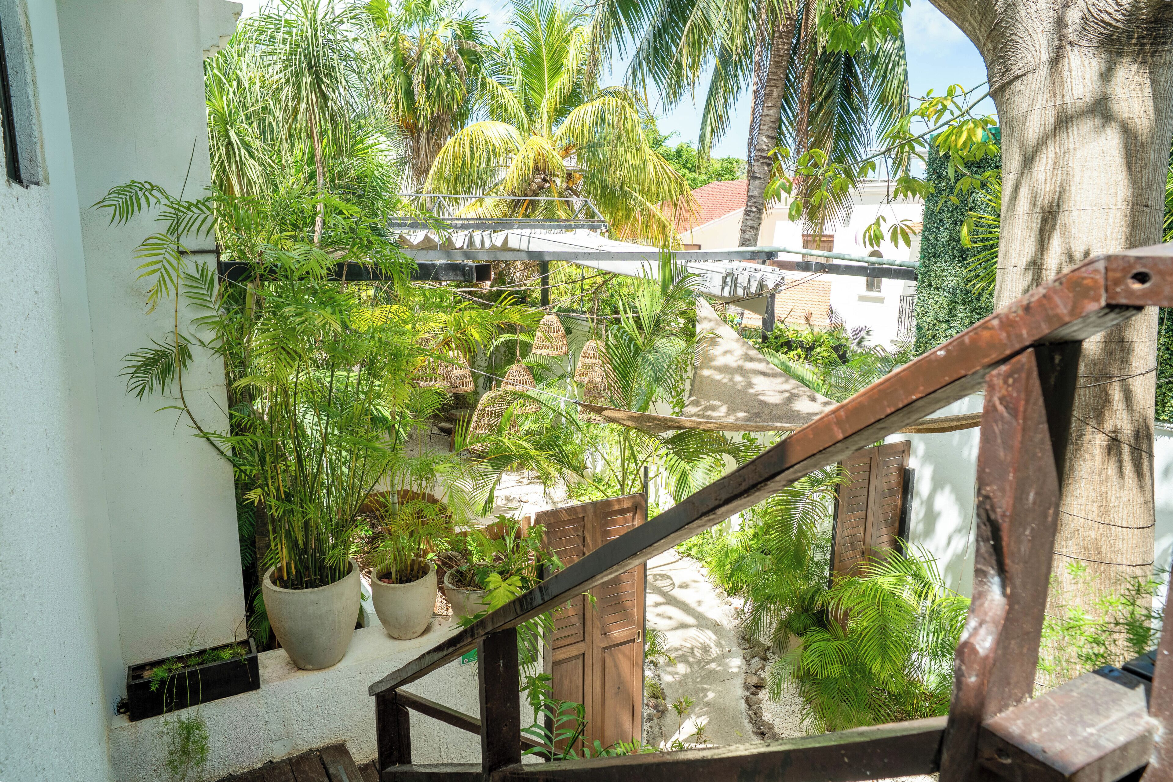 Una escalera conduce a un balcón con macetas y vistas a una zona residencial.