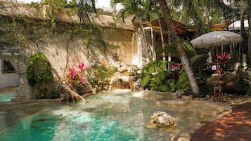 Una piscina al aire libre, sombrillas, sillones reclinables de piscina