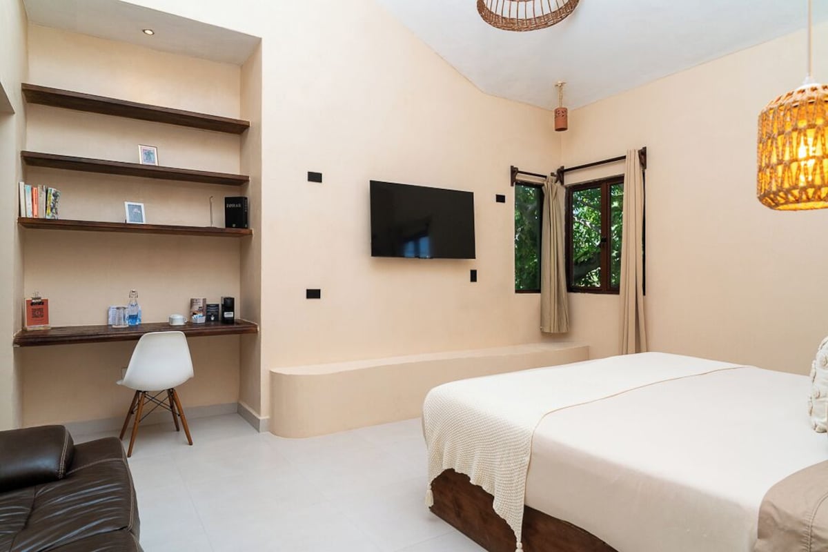 A hotel room with a bed, a desk, a chair, a television, and a window with curtains.