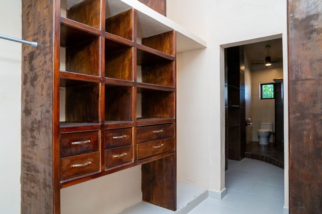 Un corridoio con un mobile contenitore in legno e una porta che conduce al bagno.