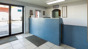 A reception area with a blue counter, a door leading outside, and a 'Welcome' sign on the wall. - OYO Hotel Pensacola I-10 & Hwy 29 (Pensacola)