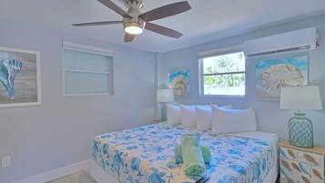 A bedroom with a bed, ceiling fan, artwork, and a window.