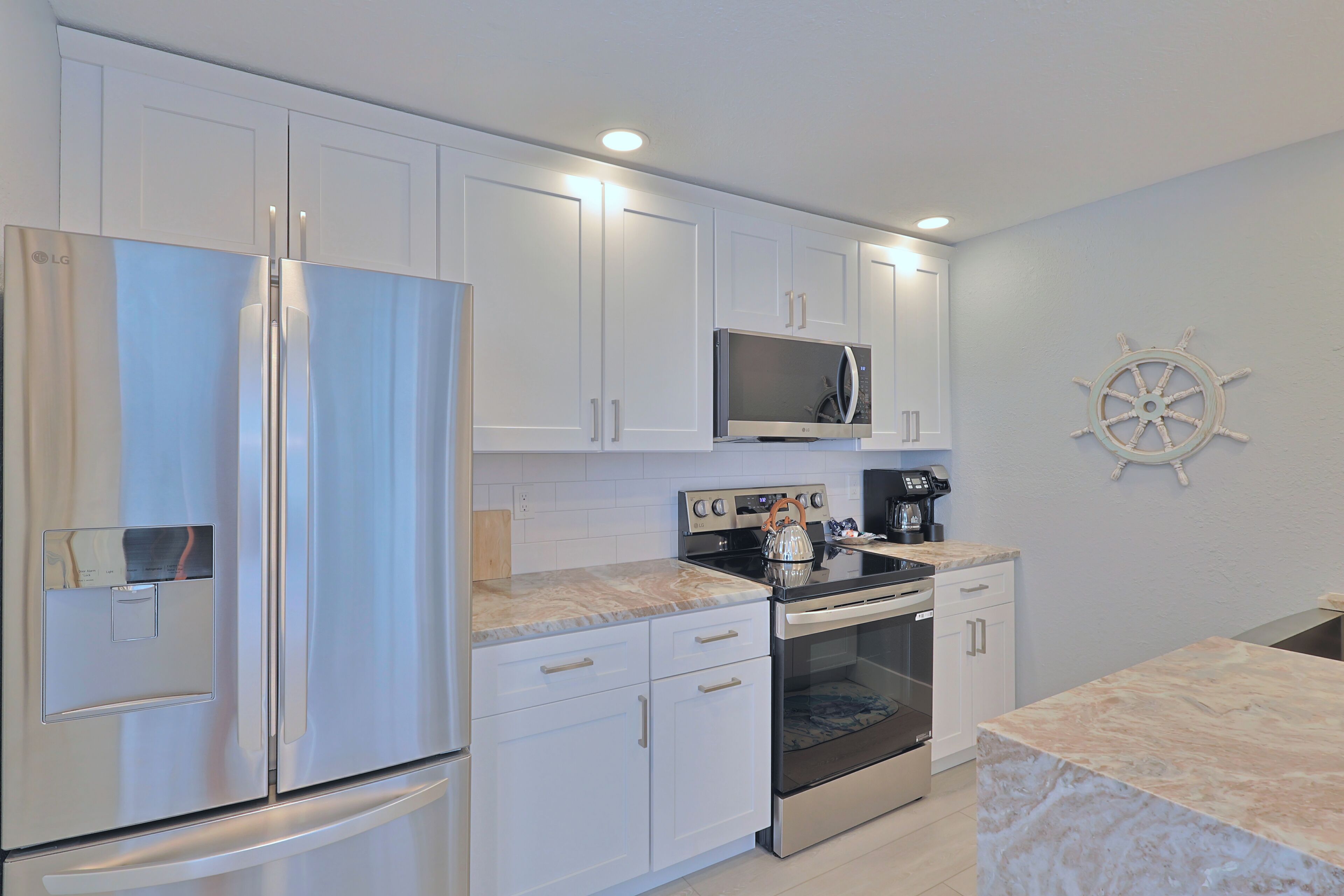 A modern kitchen with white cabinets, stainless steel appliances, a microwave, and a coffee maker.