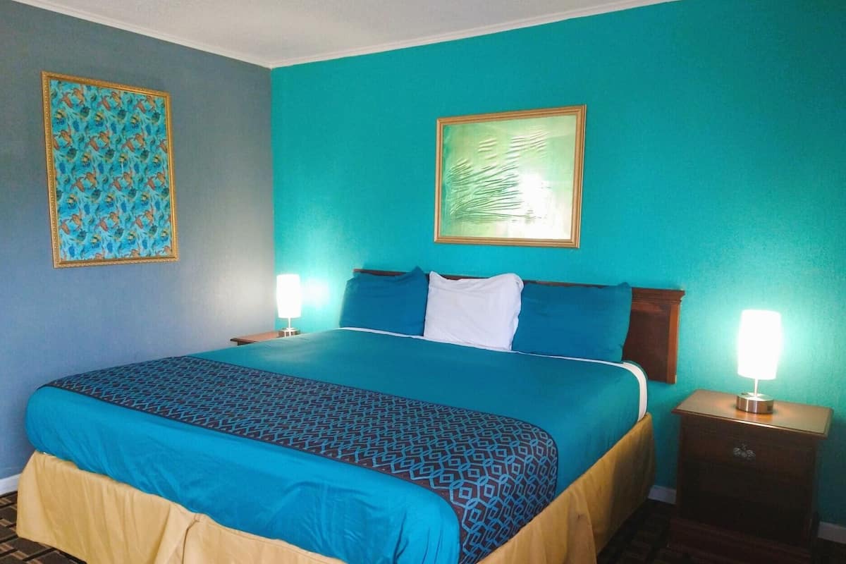 Une chambre d’hôtel avec un grand lit, deux tables de chevet et une petite table de nuit.