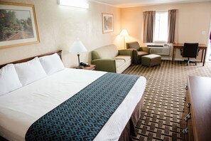 Ein Hotelzimmer mit einem großen Bett, einer Couch, einem Schreibtisch und einem Sessel.