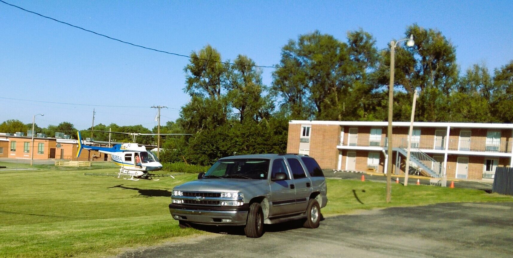 A silver SUV parked on a grassy area with a building in the background.