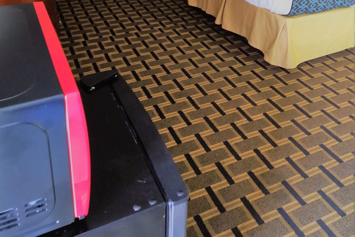 Une chambre d’hôtel avec deux lits, un bureau, une chaise, une télévision et une moquette à motifs.