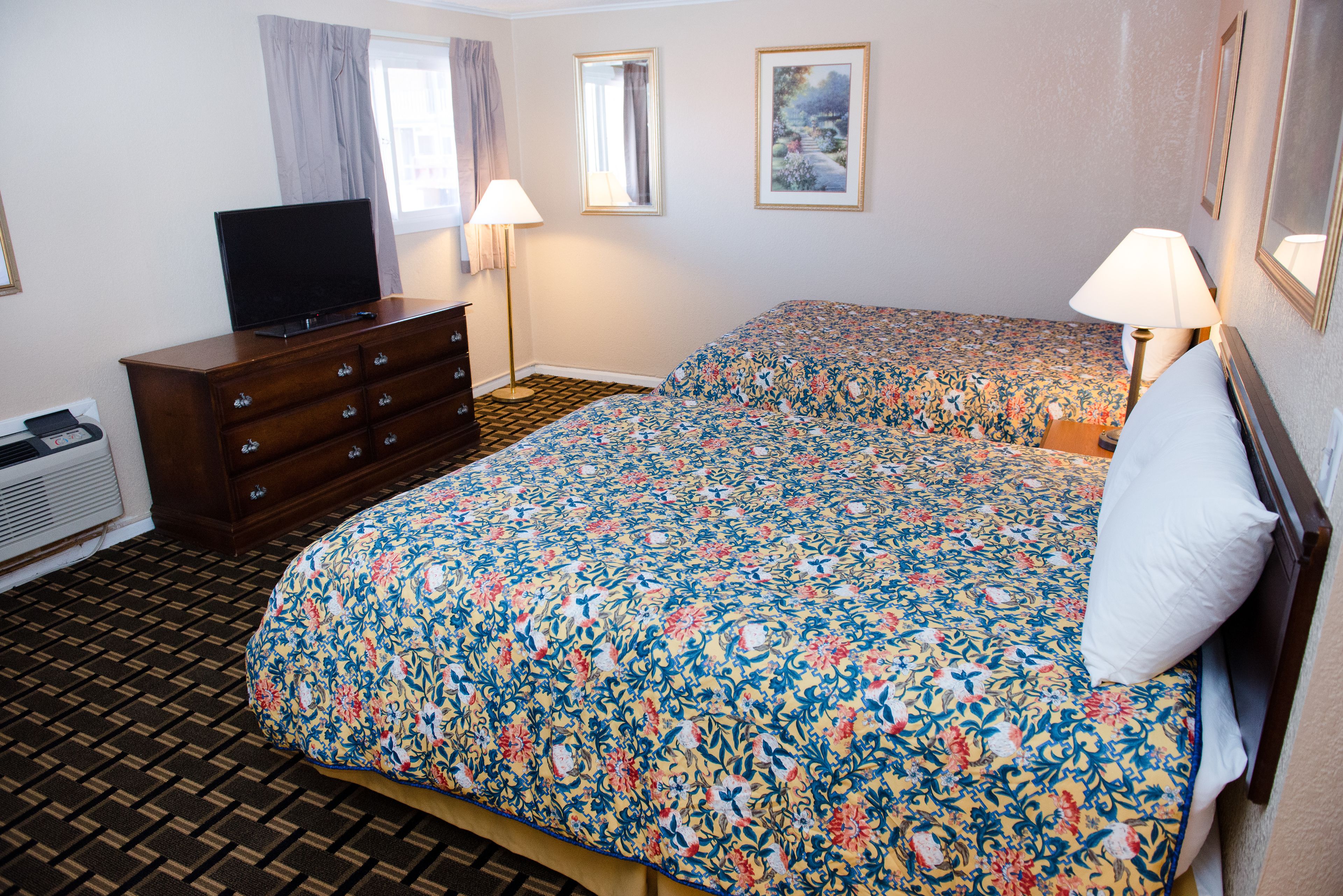 Una habitación de hotel con cama, cómoda, televisor y dos lámparas.
