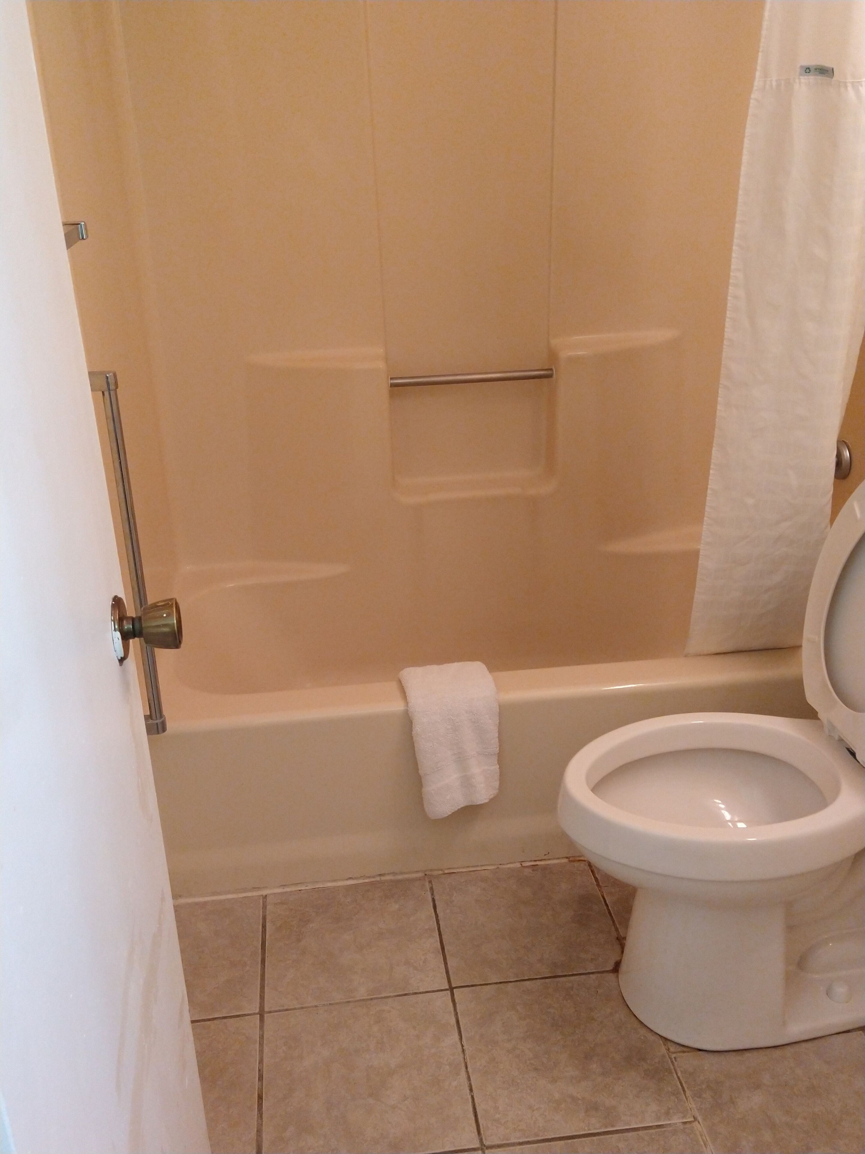 A bathroom with a bathtub, toilet, and a towel hanging on the wall.
