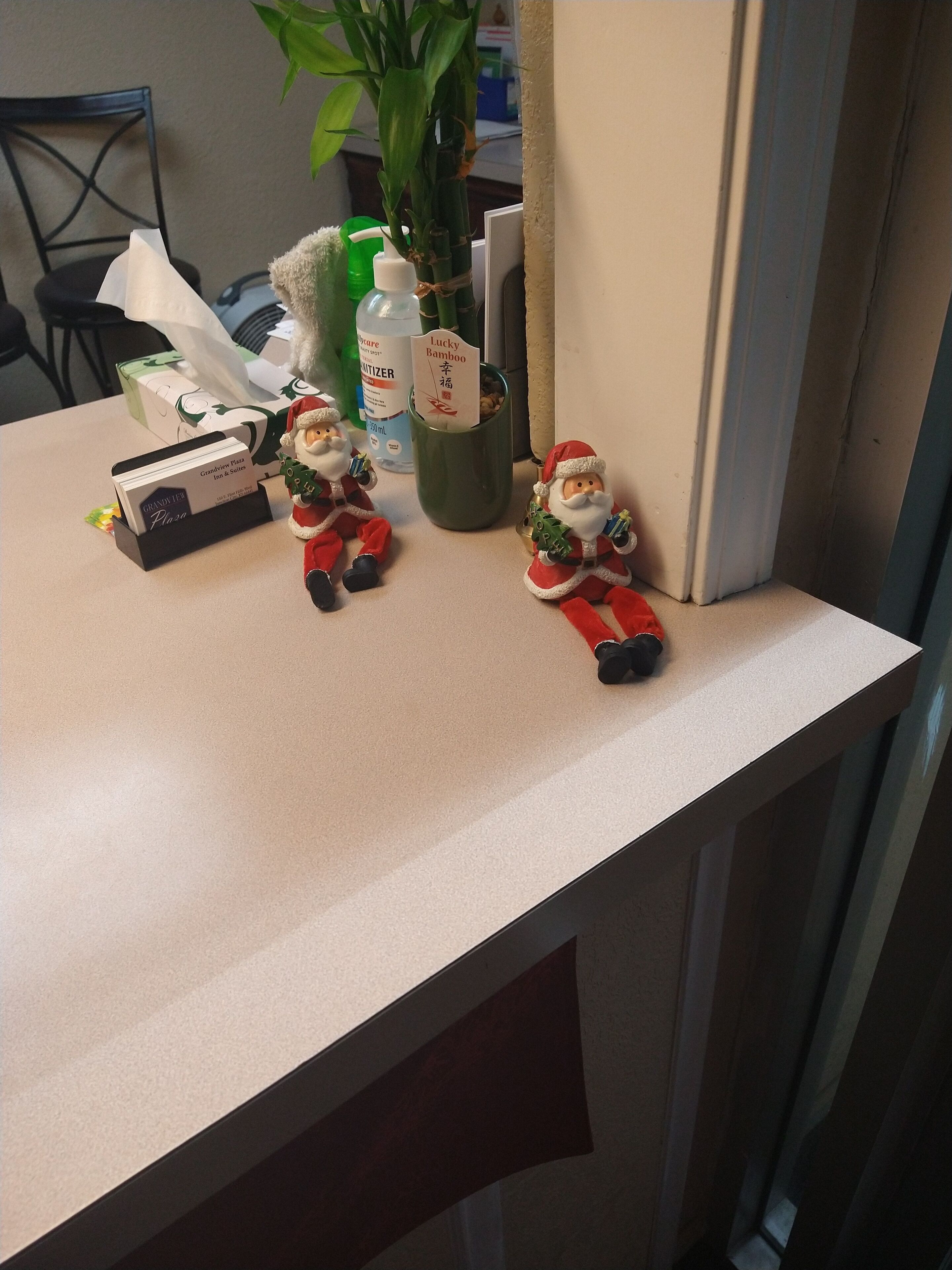 Eine Küchenarbeitsplatte mit einer Taschentuchbox, einer Handdesinfektionsmittel-Flasche, einer grünen Tasse und zwei Weihnachtsmänner-Figuren.
