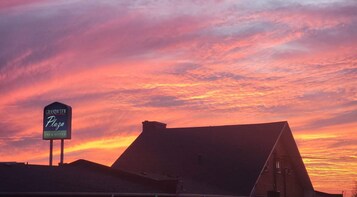 A hotel sign with "Grandview Plaza Inn & Suites" against a sunset sky.