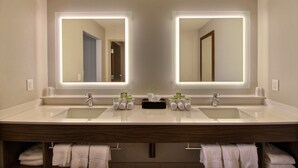 Une salle de bain moderne avec deux lavabos, un miroir et un porte-serviettes.
