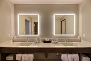 Un baño moderno con dos lavamanos, un espejo y un perchero para toallas.