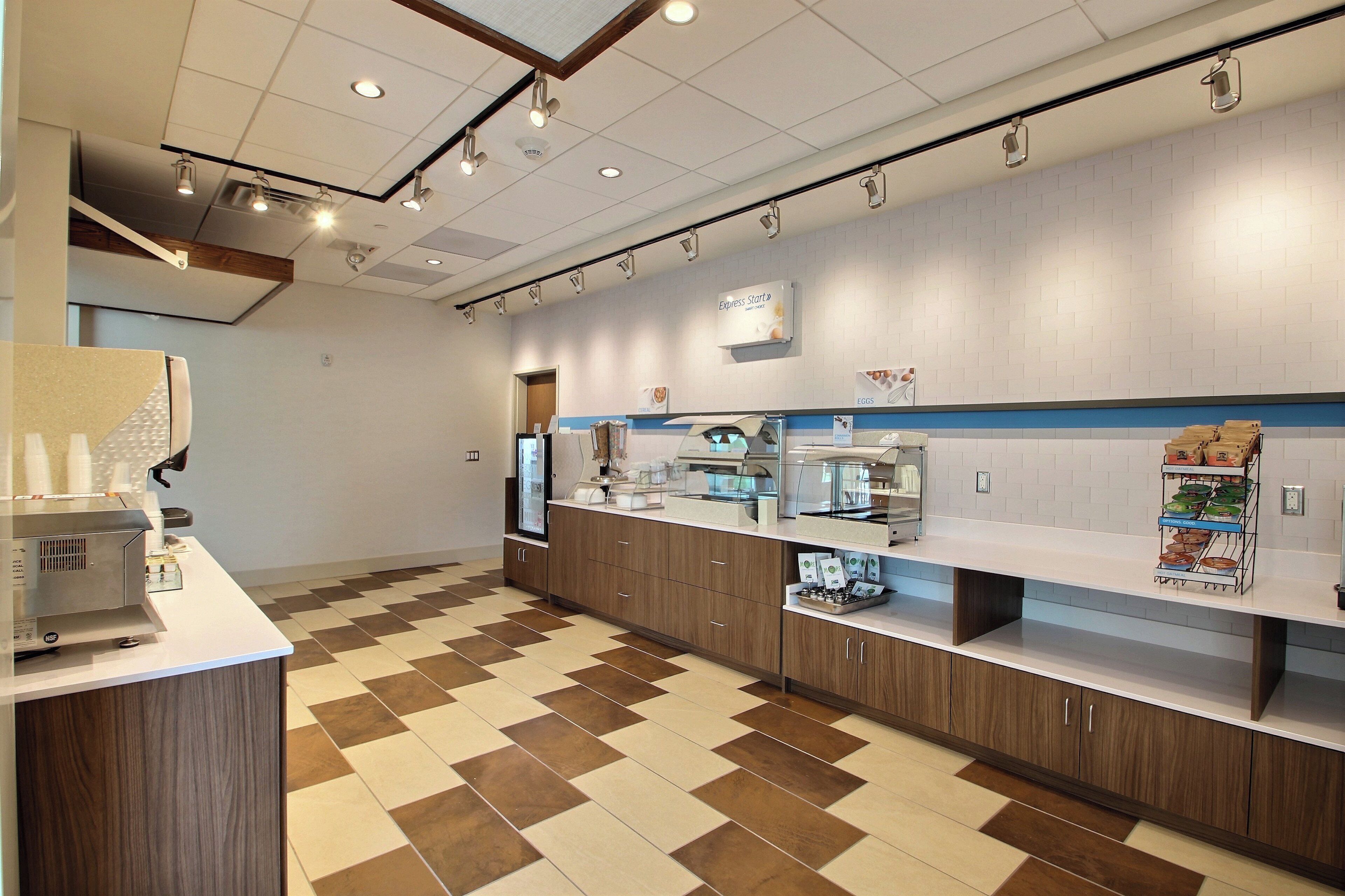 A modern kitchen area with a coffee machine, a refrigerator, and a display of food items on the counter.