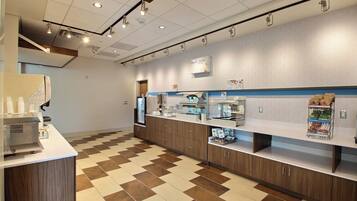 A modern kitchen area with a coffee machine, a refrigerator, and a display of food items on the counter.