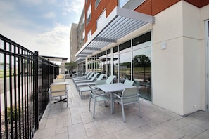 An outdoor patio with tables and chairs, a black metal fence, and a building with large windows. - Holiday Inn Express & Suites Fond Du Lac by IHG (Fond du Lac)